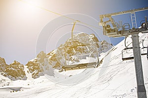 Banner panorama of ski resort, skiers on the ski lift, white snow pine trees at pink sunset or dawn