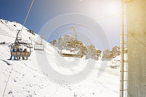 Banner panorama of ski resort, skiers on the ski lift, white snow pine trees at pink sunset or dawn