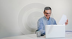 Banner panorama of young smiling cheerful businessman entrepreneur manager in bright new office working with laptop computer