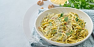 Banner with pesto pasta, bavette with walnuts, parsley, garlic, nuts, olive oil. Side view, long side, copy space, blue background photo