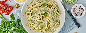 Banner with pesto pasta, bavette with walnuts, parsley, garlic, nuts, olive oil.Top view, long side, blue background photo