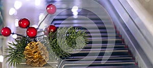 banner with piano keys with golden cone, christmas tree branch and red berries on bokeh background. New Year or