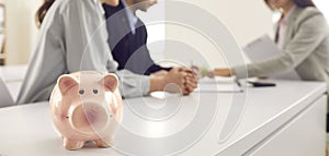 Banner with piggy bank and young couple consulting financial advisor or bank manager