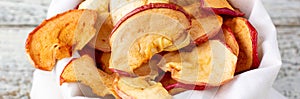 banner of A pile of dried slices of apples in white pouch on wooden background. Dried fruit chips. Healthy food