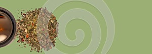 Banner with pile of healthy herbs near a cup of herb tea isolated at solid green background with copy space. Concept healthy diet