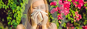 BANNER Pollen allergy concept. Young woman is going to sneeze. Flowering trees in background long format