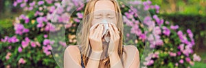 BANNER Pollen allergy concept. Young woman is going to sneeze. Flowering trees in background long format