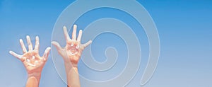 Banner of positive symbol drawing by sunscreen (suncream, suntan lotion) on two Caucasians open hands on sky background.