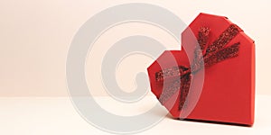 Banner with red gift box in a heart shape with ribbon bow.