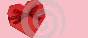 Banner with red gift box in a heart shape with tied glittering ribbon.