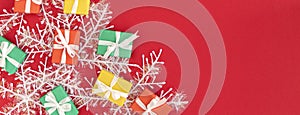 banner with Red, green and yellow gifts on a redbackground with space for text. Colorful scattered Christmas gifts