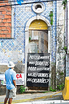 Banner in Salvador - vertical viewTranslation: How many need to die to invest in house renovations