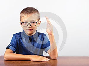 Banner Schoolboy in a blue shirt sitting at the table. Boy with glasses on white background Concept back to school