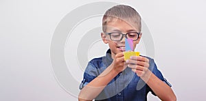 Banner Schoolboy in a blue shirt sitting at the table. Boy with glasses on white background Concept back to school