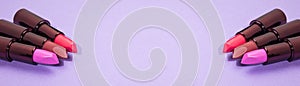 A banner of several tubes of lipstick on a purple background. Space for your text