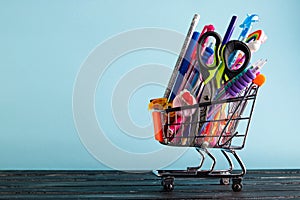 Banner of Shopping cart with school supply on a blue background with copy space. Back to school