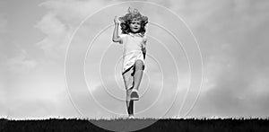 Banner with spring child face. Little boy running and jumping on the grass near a spring green meadow on blue sky. Happy