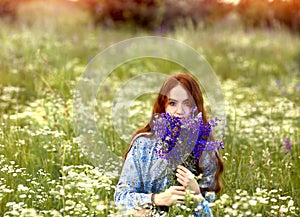 Banner with a stunning young girl looking at the camera, a redhead holding a bouquet of lilac lupins in her hands. Background blue