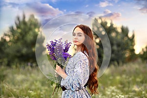 Banner with a stunning young girl looking at the camera, a redhead holding a bouquet of lilac lupins in her hands. Background blue