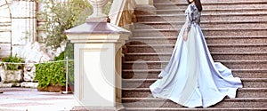 Banner with a stunning young woman in a gray elegant dresses on stone steps.