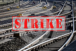 Banner with text STRIKE over lots of railroad tracks and switches, trade union concept for fair pay and working conditions in the