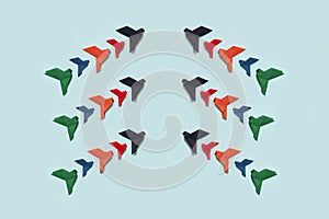 banner three groups of ten paper origami pigeons black, red, orange, blue and green fly up facing each other on light