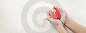 banner with top view of children hands holding red heart on white textured background. Concept of health care, love