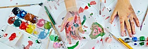 Banner Top view Little girl with painted colorful watercolor hands, child sitting at the table and drawing,