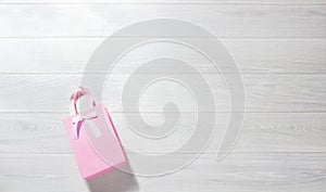 Banner Valentine pink paper giftbag on white wooden background. Top view, copy space valentine`s concept. Birthday gift bag.