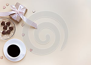 Banner of Valentine`s Day. A Cup of coffee, a gift box and a heart-shaped chocolate on a neutral beige background
