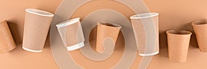 Banner with variety of paper coffee cups over light brown background