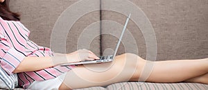 Banner website asian young woman working online laptop with smile and happy sitting on couch at living room, girl using notebook