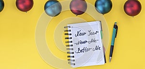 banner with Writing in a notebook New year, new me on yellow background with Christmas balls. Happy new year quote. Top