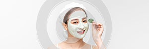 Young girl with a cleansing cosmetic mask on her face poses with a green leaf. Banner