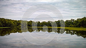 Bannes Lake on Rue Du Lac in France. Sky and trees reflected in a mirror image