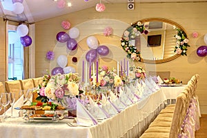 A banquet hall with a set table, a wall decorated with purple balloons and a mirror