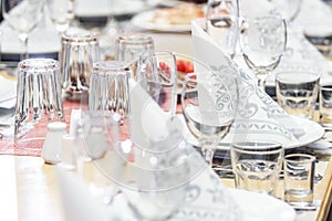 A banquet table with glasses, dishes and serviettes