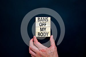 Bans off my body symbol. Concept words Bans off my body on wooden blocks on a beautiful black table black background. Women rights