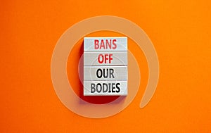 Bans off our bodies symbol. Concept words Bans off our bodies on wooden blocks on beautiful orange table orange background. Women