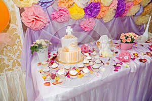 Baptism candy bar, angel statue, cupcakes, unfocused cake. Mastic cross on cake for christening child party.