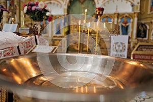 Baptismal font with blessing water and wax candles for Newborns baptism rite in Orthodox church