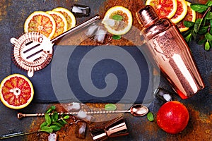 Bar accessories, drink tools and cocktail ingredients on rusty stone table. Flat lay style