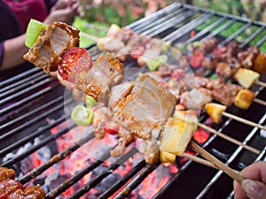 Bar-B-Q or BBQ with kebab cooking. coal grill of pock meat skewers with pineapple and green pepper. barbecuing dinner.