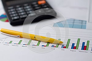 Bar chart on paper sheet, pen and calculator