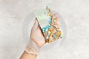 Bar of chocolate decorated with sweets and seashells in the hand of confectioner