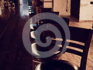 Bar counter with high chairs in empty cosy restaurant. Chairs in row in bar with lights