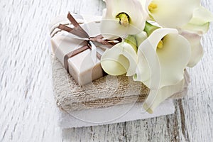 Bar of handmade natural soap, towels and bouquet of white calla flowers