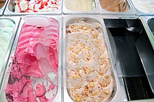 Bar with many flavors of delicious ice cream for sale. Fridge with creamy of hazelnut flavors, raspberry and cherry in container.