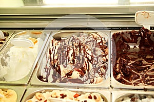 Bar with many flavors of delicious ice cream for sale in summer Fridge with creamy vanilla ice cream with chocolate dressing.