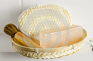Bar of orange Himalayan crystal Salt Soap on wooden tray with cleaning bath sponge in bathroom.